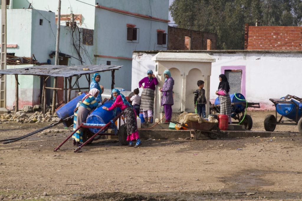 In a town somewhere along the highway, girls collect drinking water from the town well.