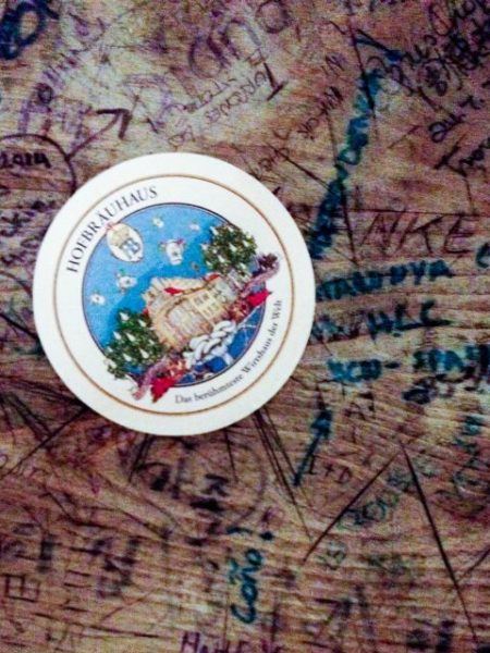 Hofbrauhaus table with grafitti and a coaster.