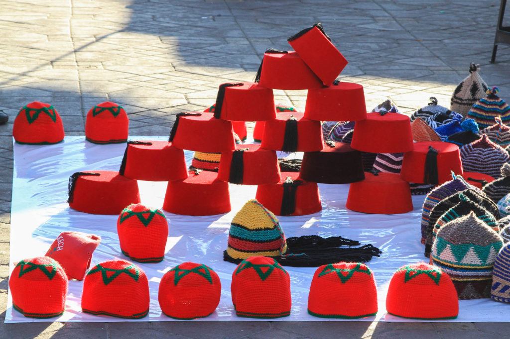A vendor sells traditional red fez hats in the Jemaa el Fna market.