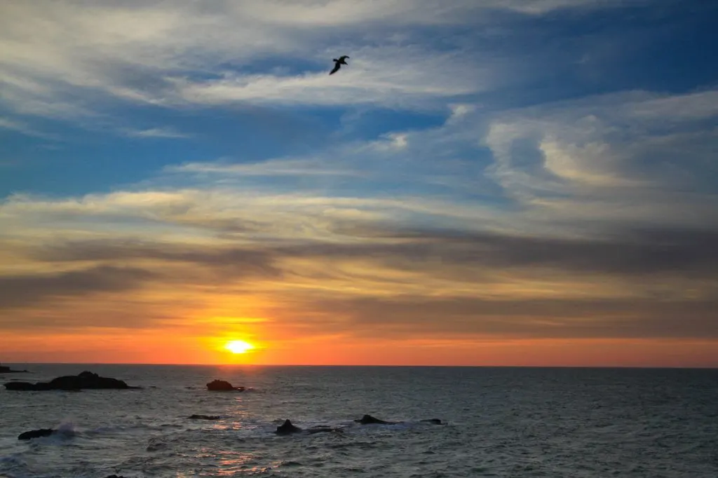 The sky above the Atlantic Ocean is painted yellow and orange as the sun sets in Essaouira.