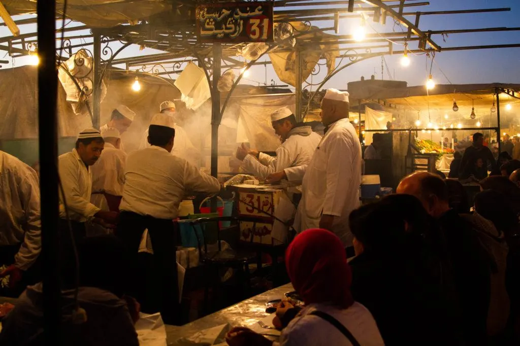 Food stall cooks work over steaming pots and grills to make Moroccan street food for crowds of people in Jemaa el Fna.