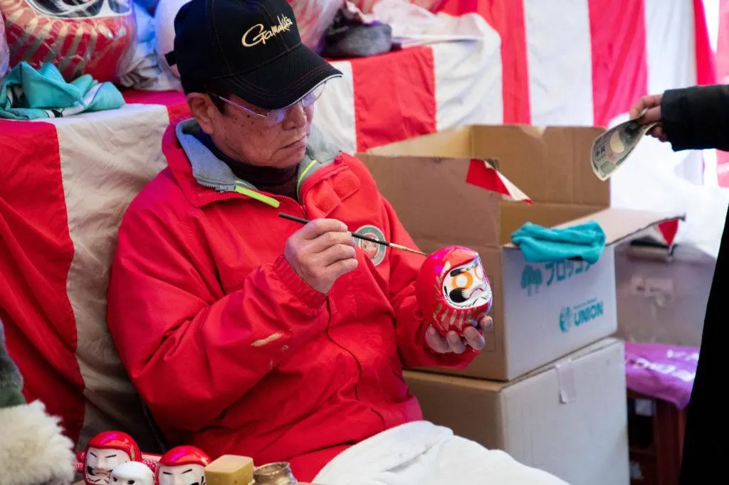 Vendor painting a message on a daruma.