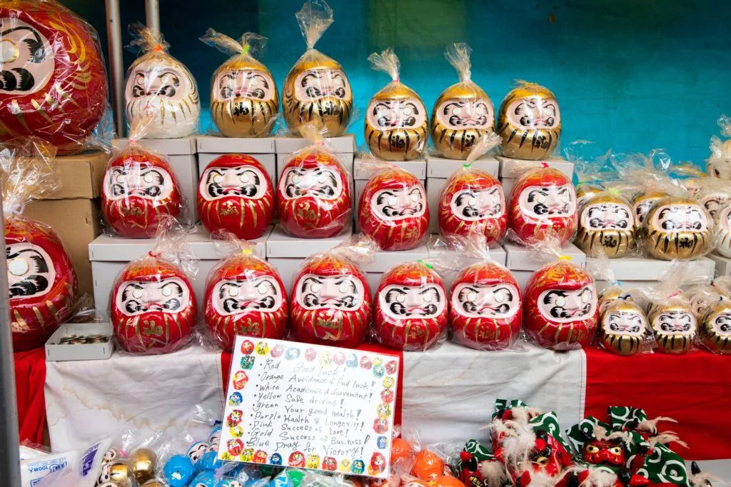 Traditional red Daruma and gold painted daruma for sale at the Daruma Festival.