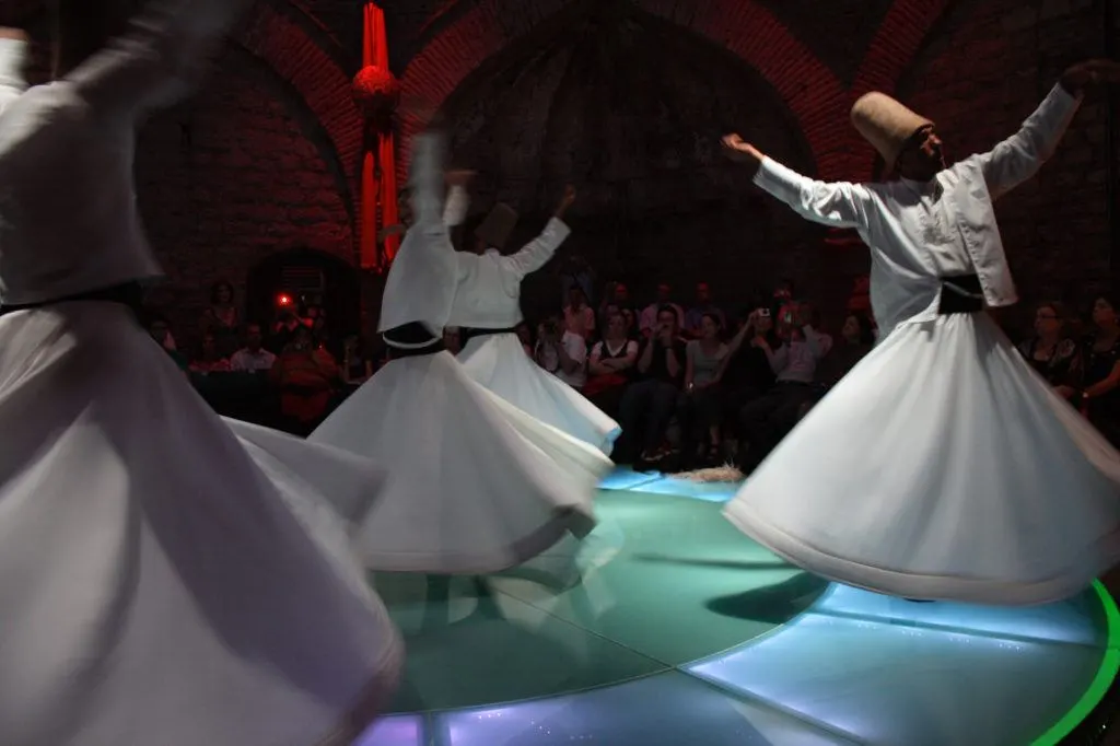 Whirling Dervishes twirl amid multi-colored lights.