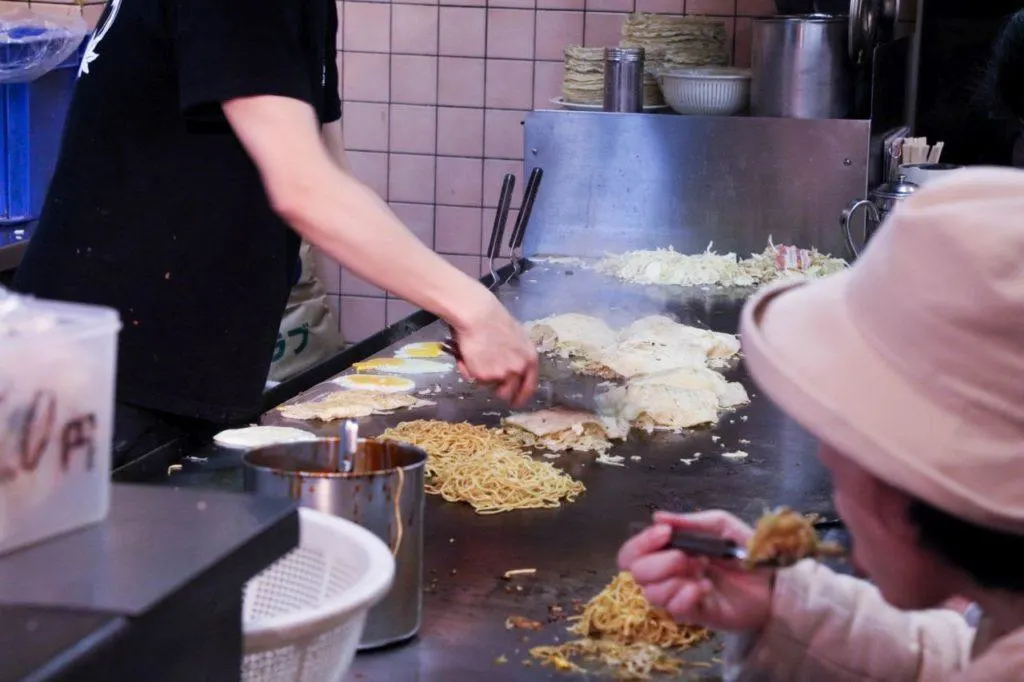 Frying the okonomiyaki and one person eating it