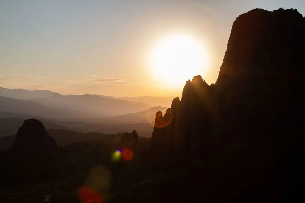 Meteora sunset silhouettes the massive rock formations.