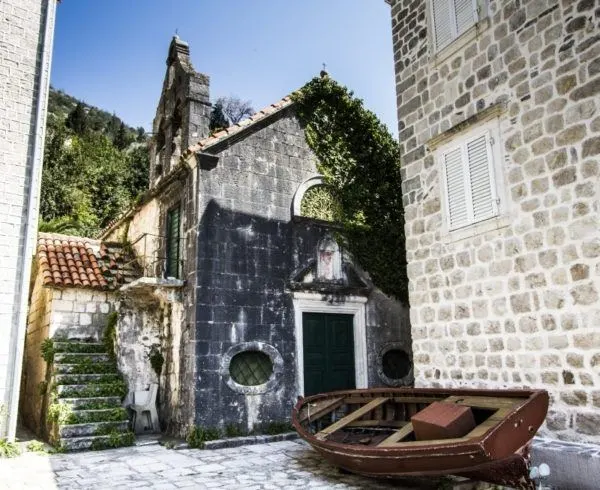Old fishing boat near ancient stone buildings in Perast.