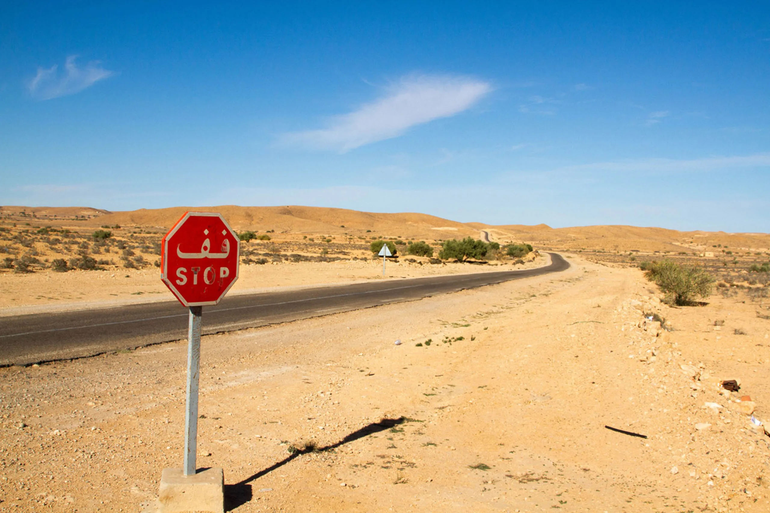 A stop sign along the road through the Sahara Desert, making a Tunisia road trip easy to navigate.