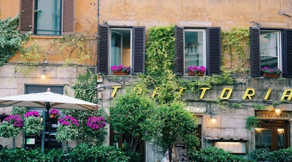 A "trattoria" sign hidden by gorgeous spring flowers.