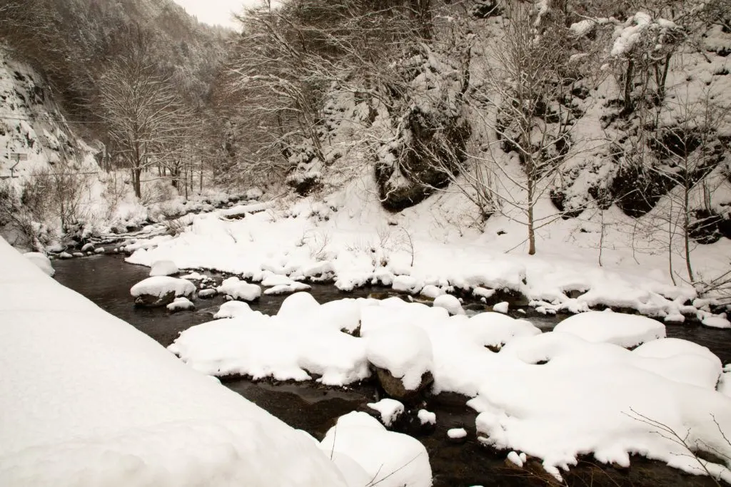 Snow piled high on the rocks in the Shiro River, Japan.