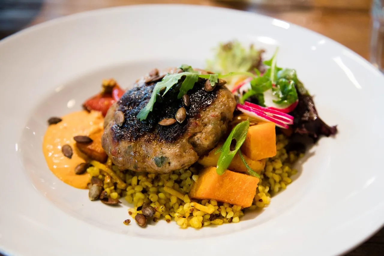 Turkey burger served with bulgar and sweet potato and root vegetable medley with fresh greens.