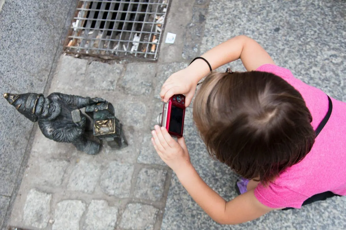 Little girl finding time to photograph the Wroclaw dwarves.