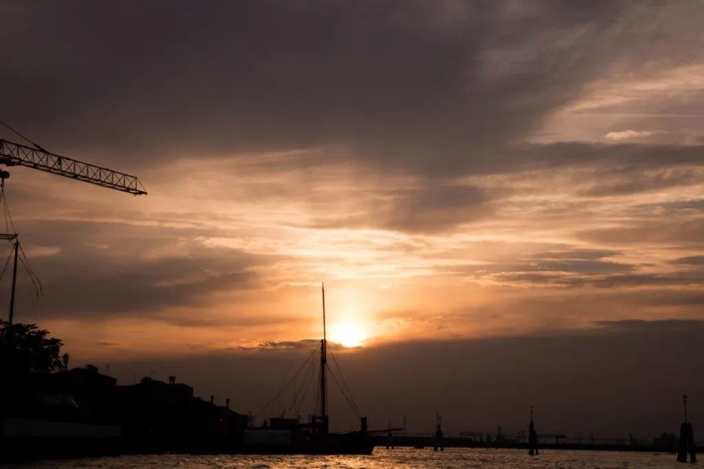The sun sets behind the harbor pf Venice.
