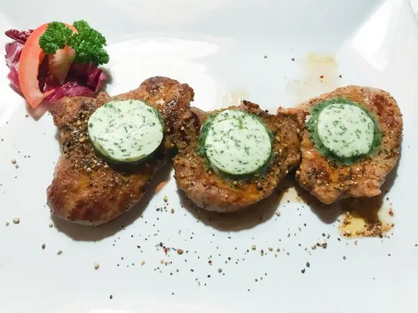 Three small steaks covered with herb butter.