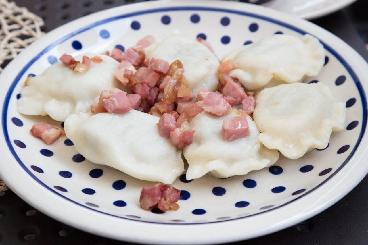 A plate of pierogies with ham and onions.
