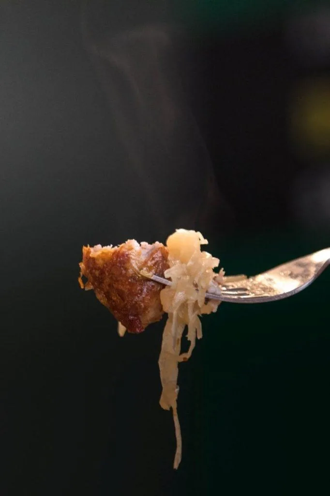 One bite of bratwurst with sauerkraut.